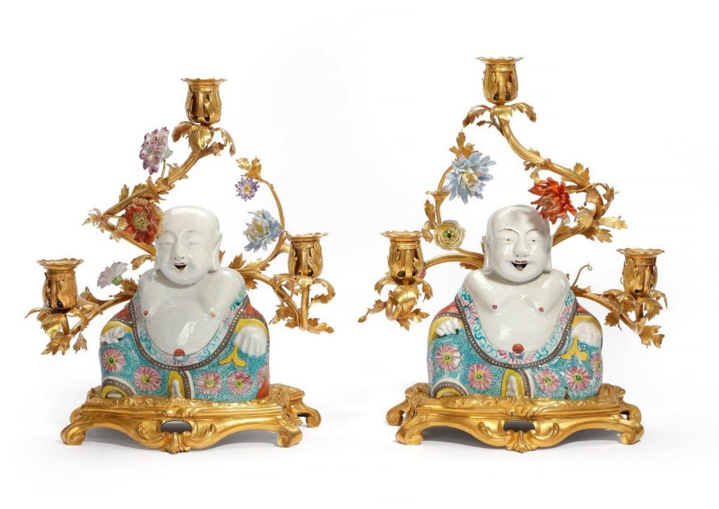 A pair of candelabras in gilt bronze from the mid-18th century. The arms are decorated with porcelain flowers from Vincennes. Porcelain buddhas from the Yongzheng period (1723-1735) sit in front of them.