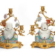 A pair of candelabras in gilt bronze from the mid-18th century. The arms are decorated with porcelain flowers from Vincennes. Porcelain buddhas from the Yongzheng period (1723-1735) sit in front of them.