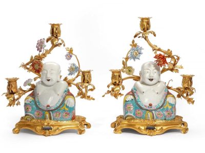 A pair of candelabras in gilt bronze from the mid-18th century. The arms are decorated with porcelain flowers from Vincennes. Porcelain buddhas from the Yongzheng period (1723-1735) sit in front of them.