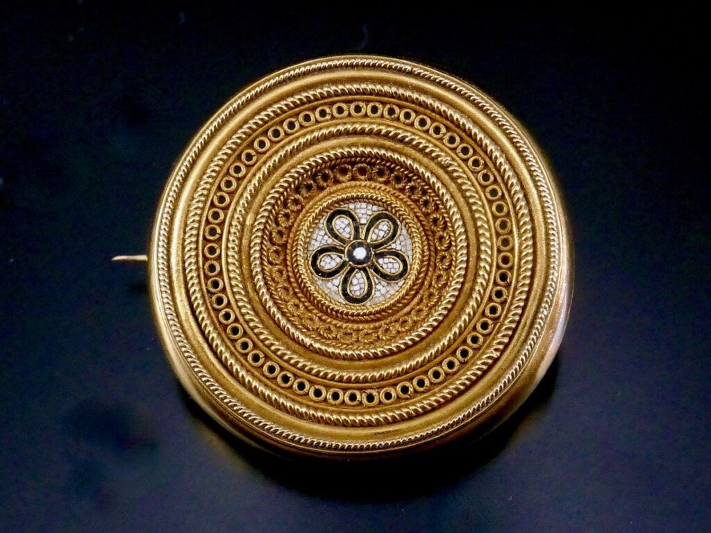 Etruscan revival brooch by Carlo Giuliano for Castellani. The gold is crafted into a fine braid and cords surrounding a rosette in micro-mosaic.