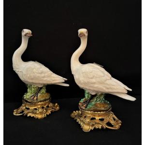 Paire de cygnes en porcelaine blanche et polychromée formant salières avec monture bronze ciselé doré.