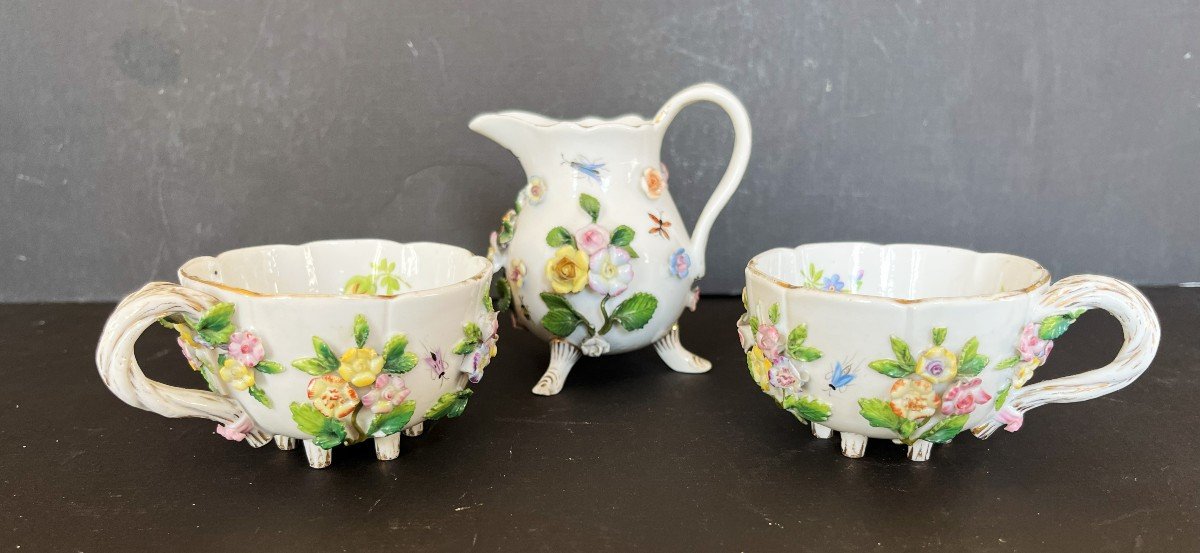 Deux Tasses Et Un Pot à Lait En Porcelaine à Décor De Fleurs En Relief Et d'Insectes.