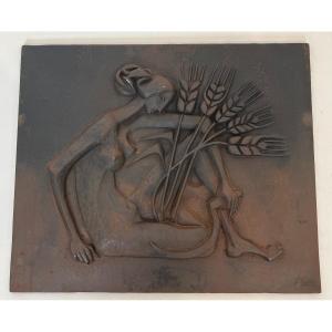 Plaque Moderniste En Fonte Représentant Une Femme Nue Tenant Une Faux Et Des Epis De Blé.