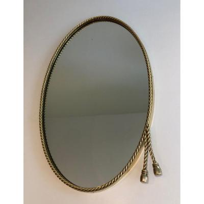 N The Style Of Maison Bagués. Oval Brass Mirror Surrounded By A Cord Decorated With 2 Pompoms. 