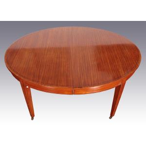 Extendable Oval Table In Satin Wood With Inverted Pyramid Legs That Rest On Metal Wheels