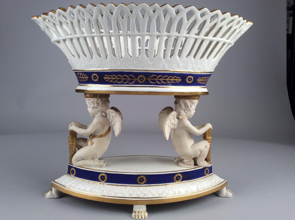 Coupe Ajourée En Porcelaine Supportée Par Deux Angelots De Style Empire, Marque Apocryphe.