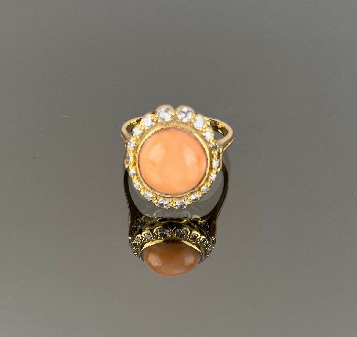 Gold Ring Adorned With A Coral Surrounded By Diamonds