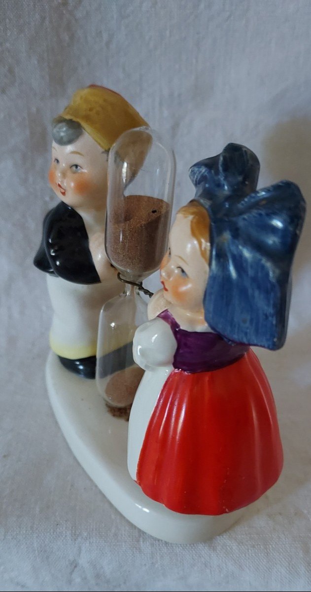 Couple Of Alsatian Children On A Tray Separated By A Glass Hourglass Timer. -photo-2