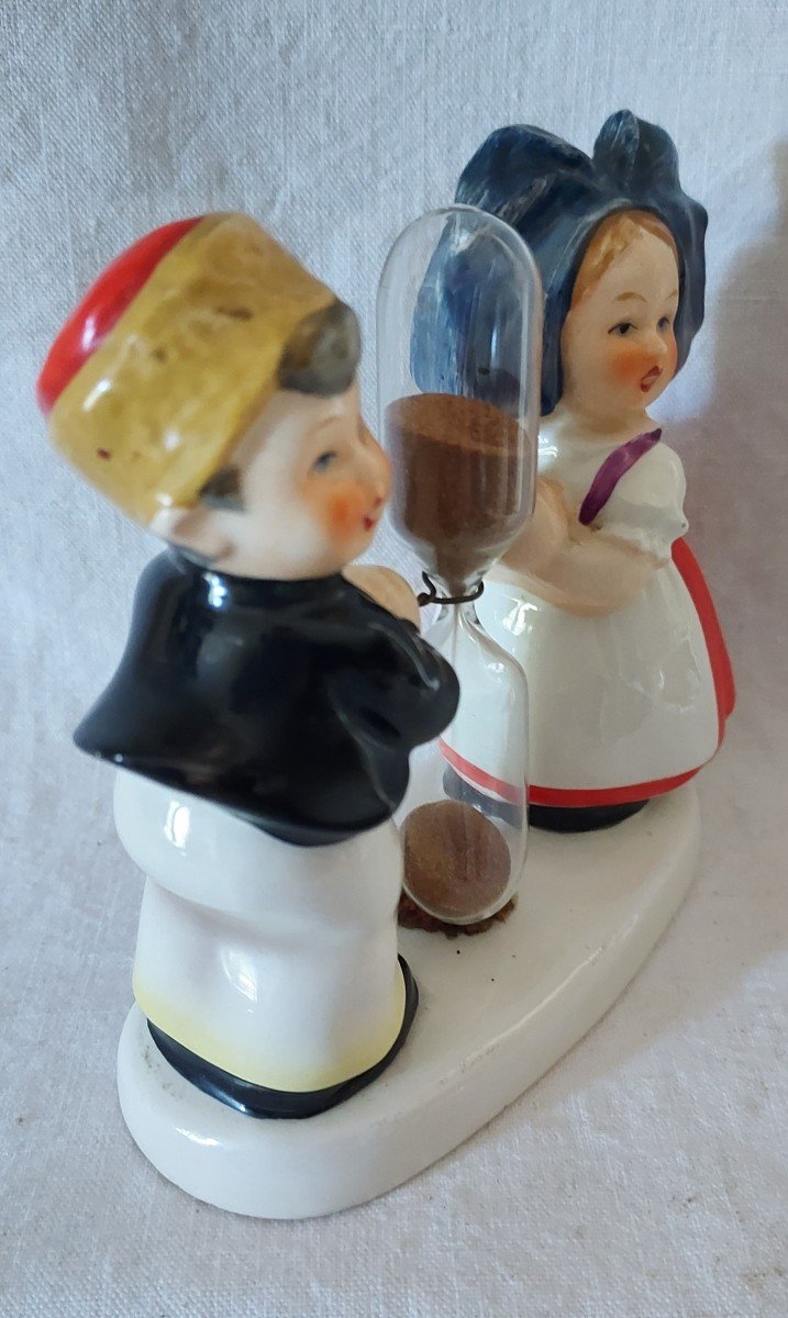 Couple Of Alsatian Children On A Tray Separated By A Glass Hourglass Timer. -photo-1