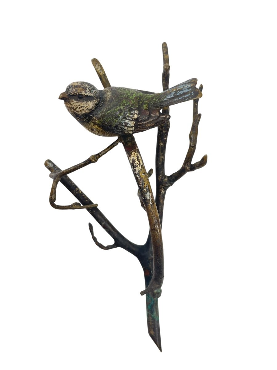 Oiseau en bronze avec peinture émaillée, posé sur une branche.