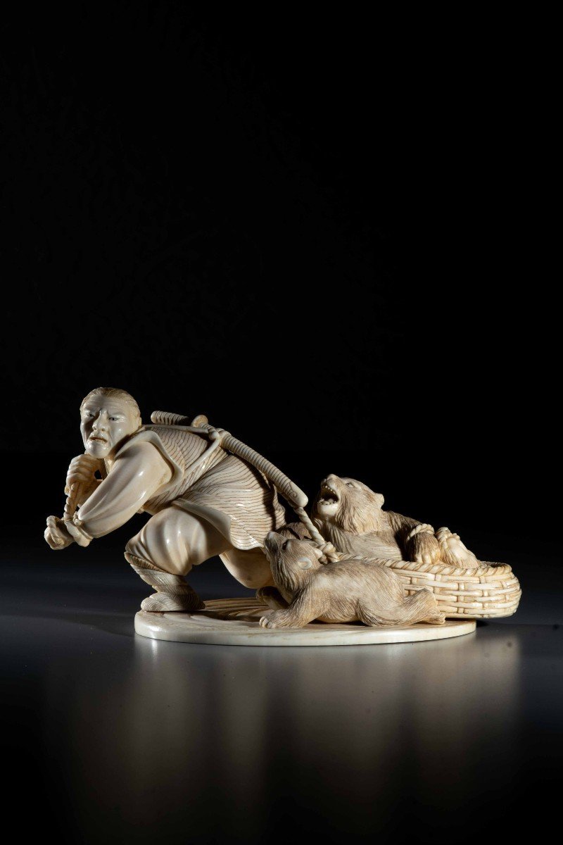 An Ivory Okimono Depicting An Ainu Hunter Dragging A Bear