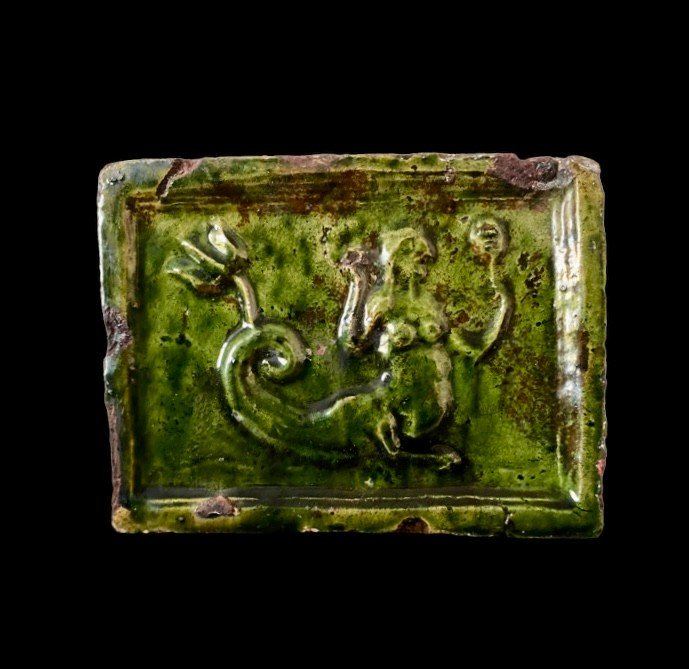 A Green Glazed Earthenware Stove Tile With A Sea Creature And A Mirror, Circa 1600